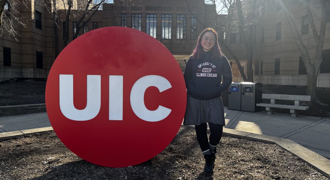 Photo of Mary next to UIC sign on campus